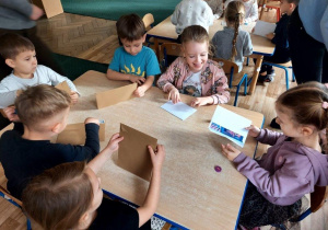 Dzieci naklejają znaczki na koperty.