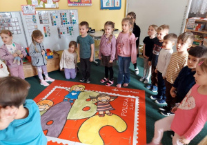 Dzieci ułożyły duże puzzle w kształcie znaczka na listy.