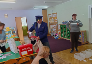 Pracownik poczty pokazuje dzieciom worek na listy oraz skrzynkę pocztową