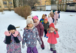 Dzieci spacerują parami po ogrodzie przedszkolnym