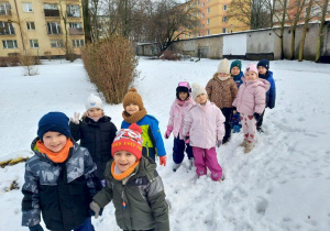 Dzieci spacerują parami po ogrodzie przedszkolnym