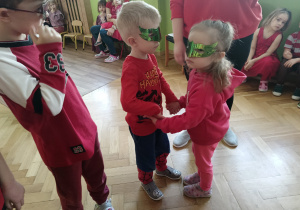 Dzieci stoją w parach. Maja na twarzach maski