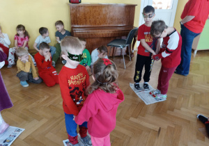 Dzieci tańczą parach na gazecie.