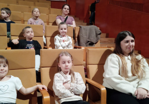 Dzieci siedzą na widowni w Akademii Muzycznej i czekają na koncert.