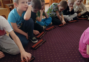 Dzieci wykonują zadania na liczydle z arytmetyki mentalnej