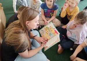 Dzieci siedzą w koło mamy Olka i uważnie słuchają bajki