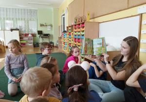 Mama Olka pokazuje dzieciom ilustracje książki