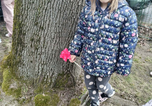 Dziewczynka trzyma w ręku kwiat z bibuły