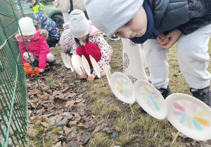 Dzieci sadzą wykonane własnoręcznie kwiaty w ogrodzie przedszkolnym