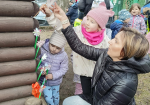 Nauczycielka ozdabia kwiatami domek w ogrodzie przedszkolnym