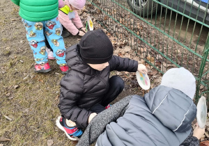 Dzieci sadzą wykonane własnoręcznie kwiaty w ogrodzie przedszkolnym
