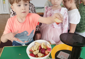 Dzieci wkładają owoce do sokowirówki