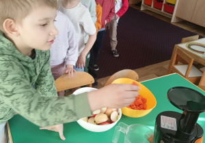 Dzieci wkładają owoce do sokowirówki