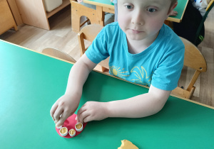 Chłopiec bawi się w dentystę i zalepia dziury w zębach plasteliną