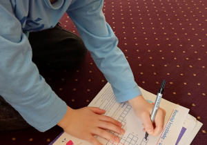 Dzieci rozwiązują krzyżówkę, w której hasła dotyczą dbania o ząbki.