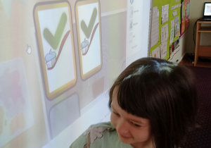 Dzieci biorą udział w grze edukacyjnej na tablicy multimedialnej