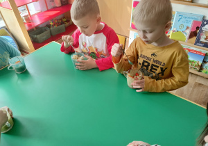 Dzieci jedzą ze smakiem sałatkę owocową zrobioną przez siebie.