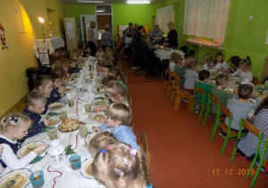 Spożywanie posiłku przez dzieci i pracowników na sali gimnastycznej