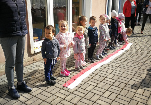 Pani Anetka i dzieci stoją w szeregu przed flagami ułożonymi jak dywan