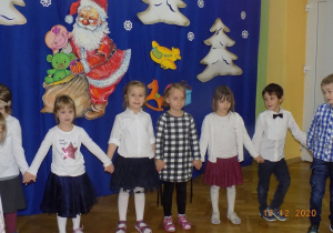 Dzieci trzymają sięza ręce i śpiewają świąteczną piosenkę.