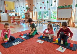 Dzieci układają piramidy z kolorowych kubeczków wg wzoru