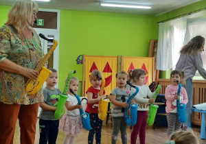 Dzieci tańczą na koncercie edukacyjnym z wykorzystaniem dmuchanych saksofonów